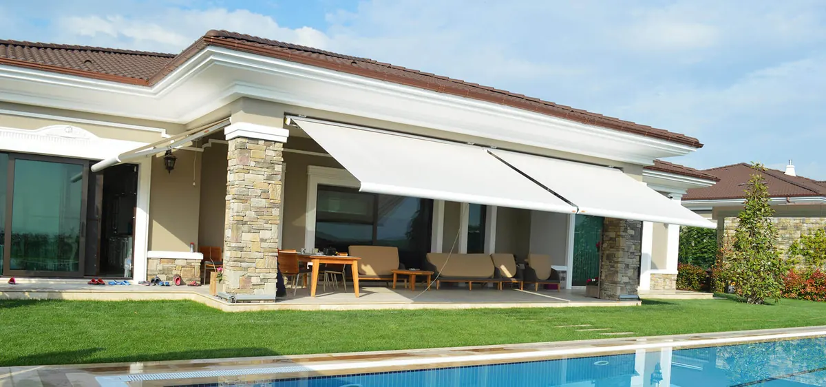 White folding-arm awning extended over a villa terrace with a pool in front