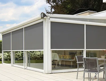 Café terrace enclosed by grey zip screens above glazed sliding doors, with chairs and tables behind