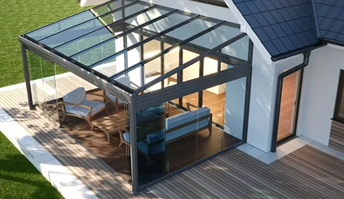 Glass-roof winter garden attached to a house, with dark frame and wooden decking