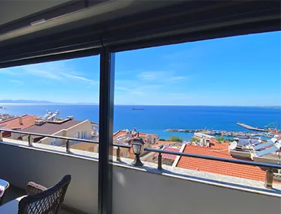 Holiday-village balcony with a sea, harbour and rooftop view through a dark frame