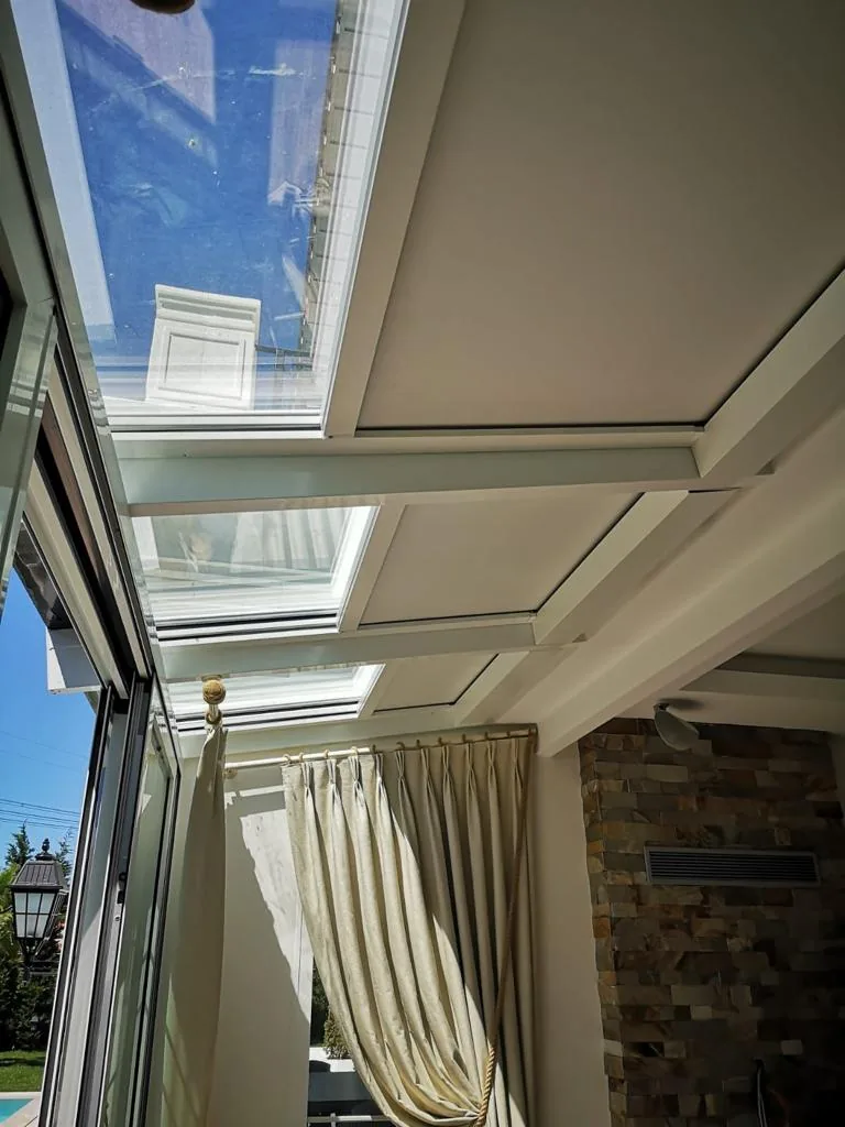 Ceiling zip screen under an office skylight with a pale curtain hanging at the side