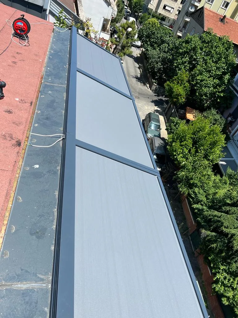 Aerial view of a long glass roof strip fitted with zip screens on a rooftop beside garden planting