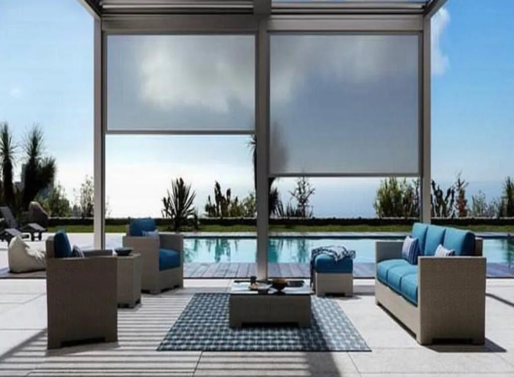Two large zip screens in a frame on a terrace with lounge seating and a swimming pool beyond
