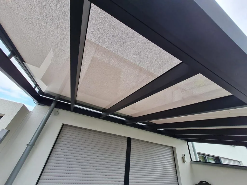 Translucent ceiling zip screen under dark pergola beams above an exterior roller shutter