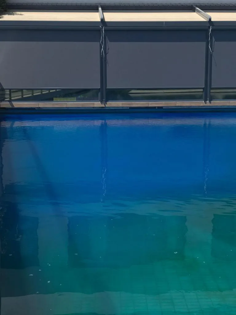 Dark zip screen lowered at the edge of a blue swimming pool