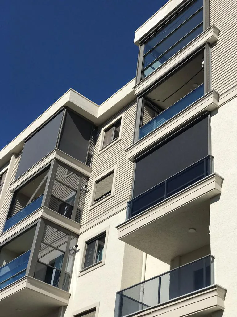 Several stacked balconies of an apartment block, each fitted with a lowered dark zip screen