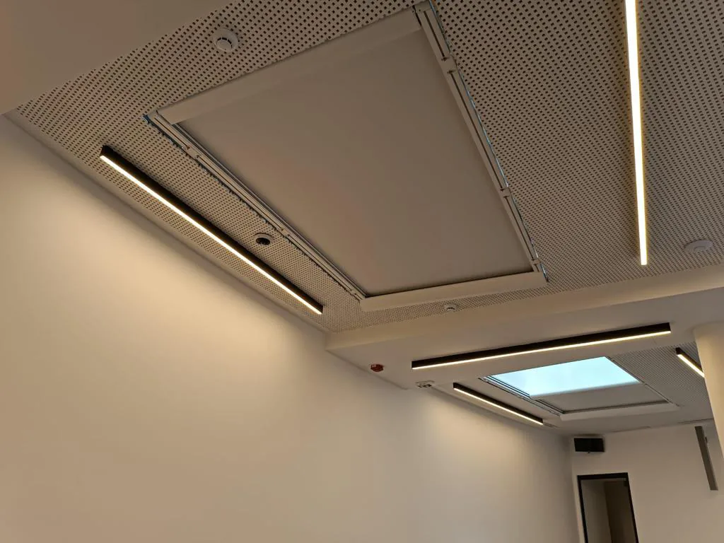 Ceiling zip screen recessed into a panelled room ceiling beside a daylight opening