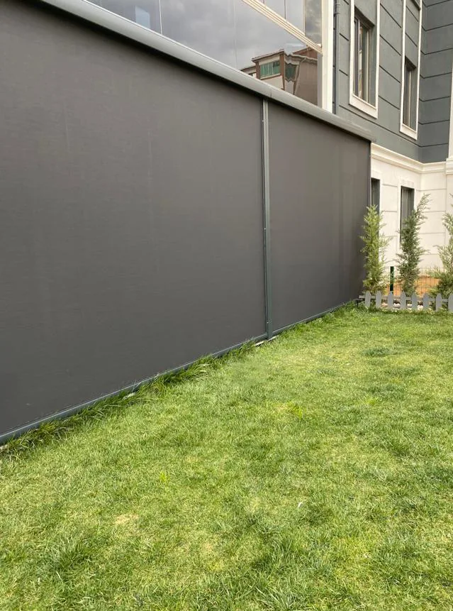Grey zip screen running along a lawn-side wall of a building, with a lawn in front