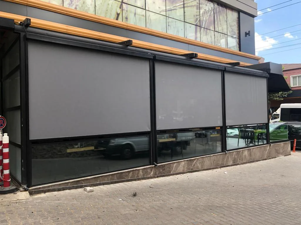 Three grey zip screens on a corner shop front with a marble plinth and street beyond