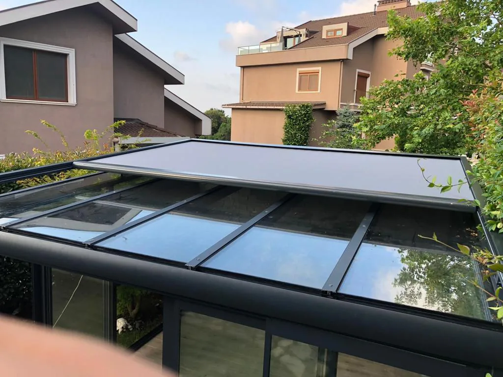 Zip screen partly covering the glass roof of a winter garden between two houses