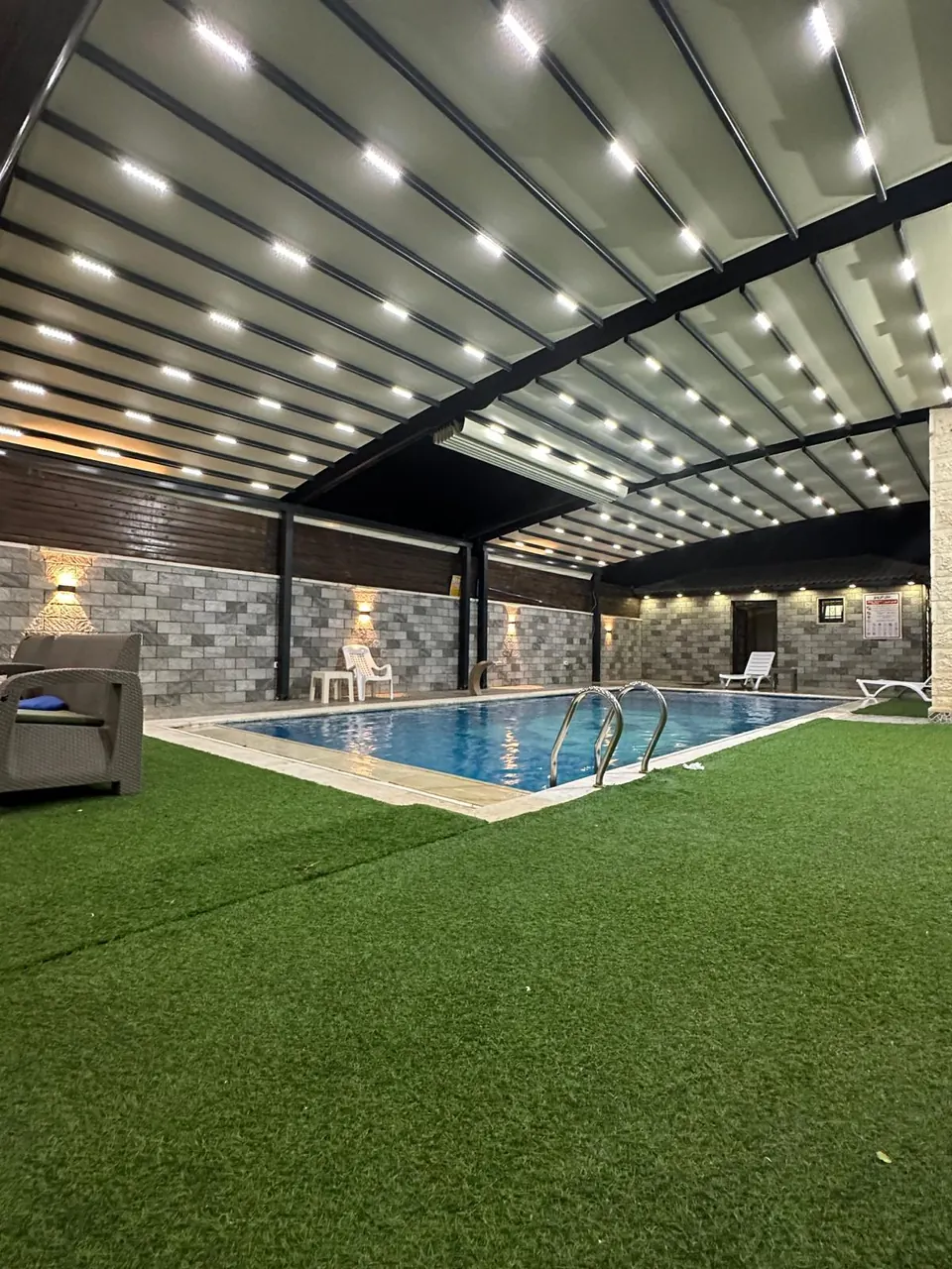 Retractable fabric roof panels with integrated lights over a covered pool terrace