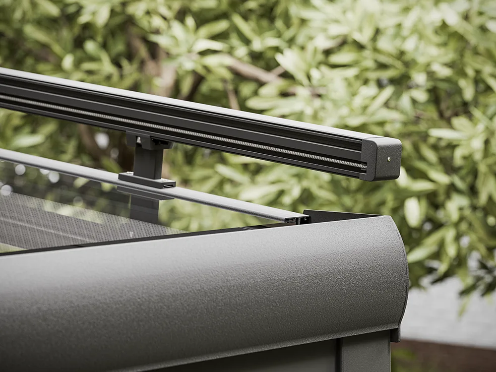 Black aluminium zip rail and headbox end cap at the edge of a glass-roof terrace