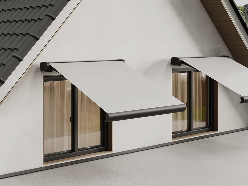 Two cassette awnings with light fabric extended over first-floor windows of a white house with a tiled roof